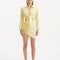 "Model wearing theGreta Yellow Shirt and Maeby Skirt from the front, showcasing its bright yellow hue, front tie detail, and stylish cropped silhouette for a lively, beach-to-city look."