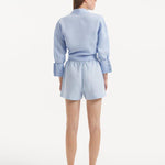 "Model wearing the Masha Baby Blue Shorts from the back, showcasing the high-waisted design, elasticated waistband, and the relaxed fit of the shorts. "