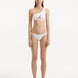 Model showcasing the Harbor White Bikini Bottom from the front, highlighting the geometric design and low waist fit.