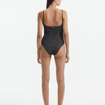 Back View: Model in Hartley Silver Swimsuit - Fully Lined, Metallic, Moderate Bottom Coverage, One Piece Swimsuit,  MOEVA Luxury Swimwear 