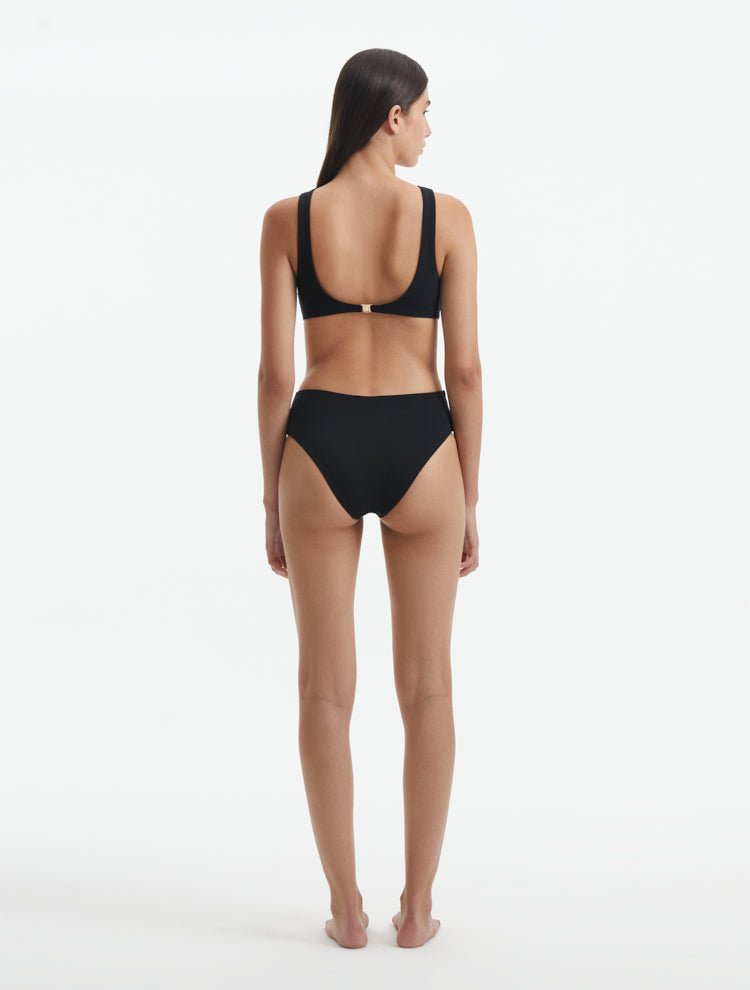 Back View: Model in Honora Black Swimsuit - MOEVA Luxury Swimwear, Low Back, Gold Clasps at the Back, Full Bottom Coverage, Fully Lined, MOEVA Luxury Swimwear