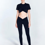 "Ida Black Leggings front view displaying a trendy ruched design and a V-shaped low waistline. The leggings' stretchable fabric provides a snug fit, combining style and functionality for various activities."