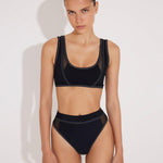 Front View: Model in Ilari Black Bikini Top - MOEVA Luxury Swimwear, Mesh Details, Scoop Neck, Color Contrasting Decorative Stitching Detail, MOEVA Luxury Swimwear 