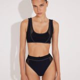 Front View: Model in Ilari Black Bikini Top - MOEVA Luxury Swimwear, Mesh Details, Scoop Neck, Color Contrasting Decorative Stitching Detail, MOEVA Luxury Swimwear 