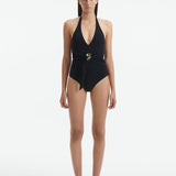 Front View of Model Wearing Imelda Black Swimsuit - MOEVA Luxury Swimwear, Halter Neck, Tie Neck, V Neckline, Draped Front Piece Detail, Removable Padding One Piece Women's Swimwear, Twisted Gold Accessory, MOEVA Luxury Swimwear   