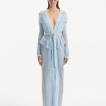 "Model wearing the Itzel baby blue kaftan from the front, showcasing its hand-knit design, translucent open knit, and dynamic fringe details, paired with a playful beach ensemble."