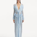 "Model wearing the Itzel baby blue kaftan from the front, showcasing its hand-knit design, translucent open knit, and dynamic fringe details, paired with a playful beach ensemble."
