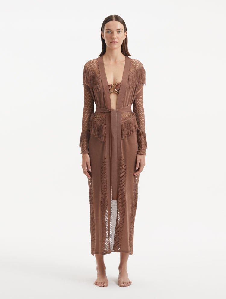 "Model wearing the Itzel brown kaftan from the front, showcasing its hand-knit design, earthy brown color, and fringed details, paired with vibrant swimwear."