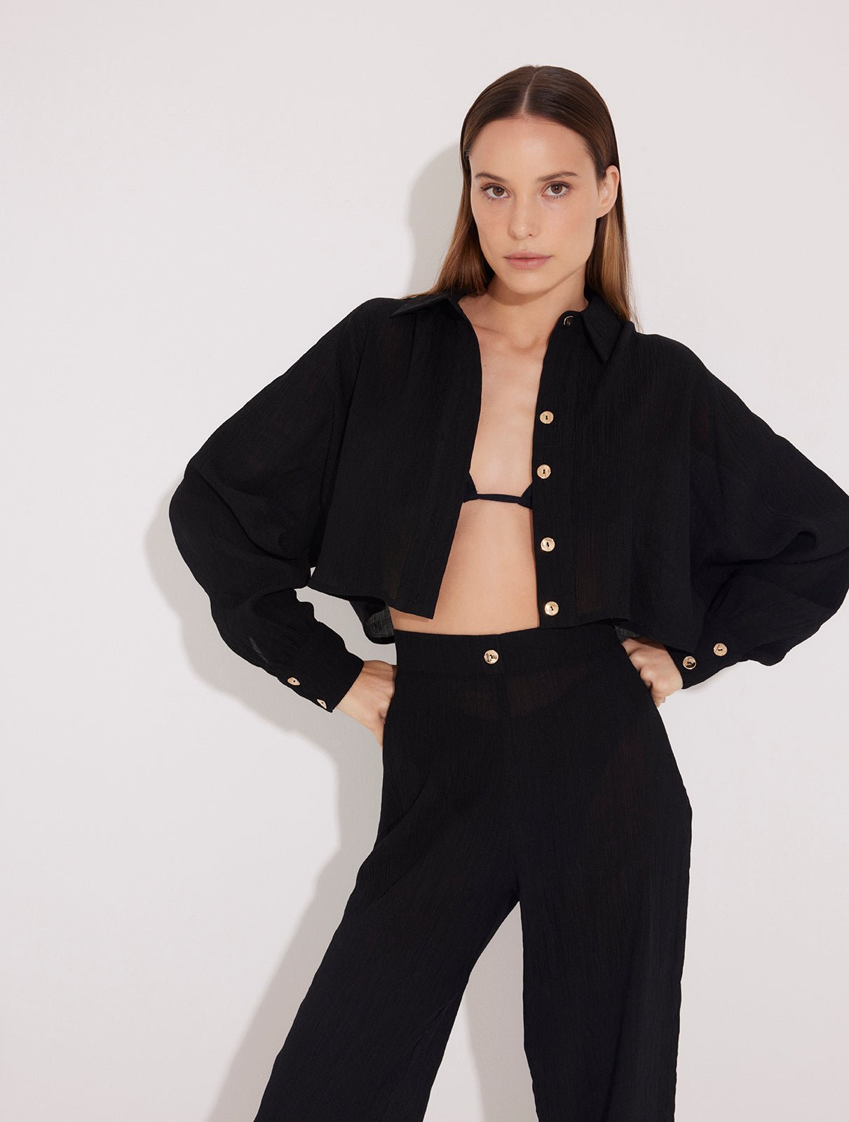 Front View: Model in Jacinta Black Shirt - MOEVA Luxury Swimwear, Cropped Shirt, Button Fastening Through Front, Soft Touch Fabric, Recycle Fabric MOEVA Luxury Swimwear