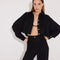 Front View: Model in Jacinta Black Shirt - MOEVA Luxury Swimwear, Cropped Shirt, Button Fastening Through Front, Soft Touch Fabric, Recycle Fabric MOEVA Luxury Swimwear