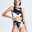 "Model wearing the Jackie Abstract Print Swimsuit from the front, showcasing the high leg cut and twist knot detail."