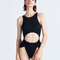 "Model wearing Jackie Black Swimsuit from the front, showcasing high leg cut, twist knot detail, high neckline, and open back with gold-plated clasp closure."