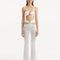 "Model wearing Jenna White Pants from the front, highlighting the high-waist, flared slim fit, and intricate cut-out details."