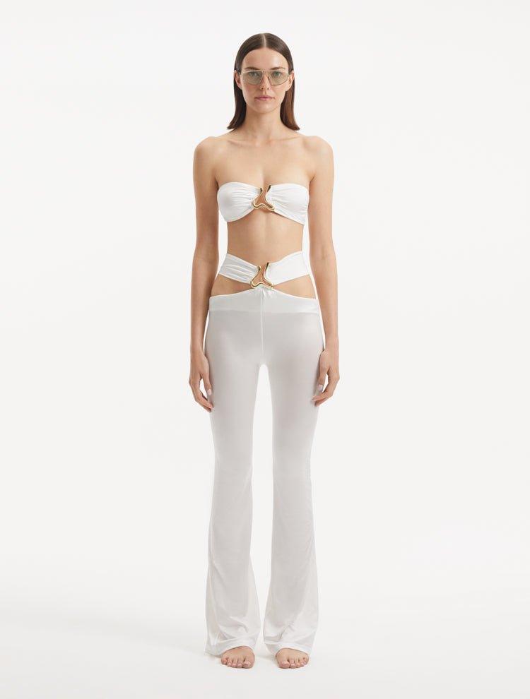 "Model wearing Jenna White Pants from the front, highlighting the high-waist, flared slim fit, and intricate cut-out details."