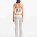 "Back view of the Jenna White Pants illustrating the flared silhouette and cut-out details, emphasizing the modern and sophisticated fit."