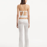 "Back view of the Jenna White Pants illustrating the flared silhouette and cut-out details, emphasizing the modern and sophisticated fit."