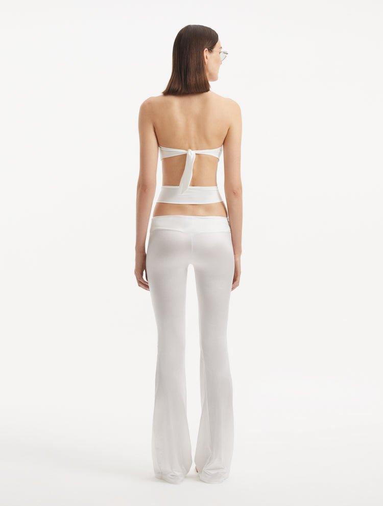 "Back view of the Jenna White Pants illustrating the flared silhouette and cut-out details, emphasizing the modern and sophisticated fit."