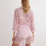 "Back view of the Jesabel Pink Dress, highlighting its mini length, button-down detail, and waist panel with a tie at the front."
