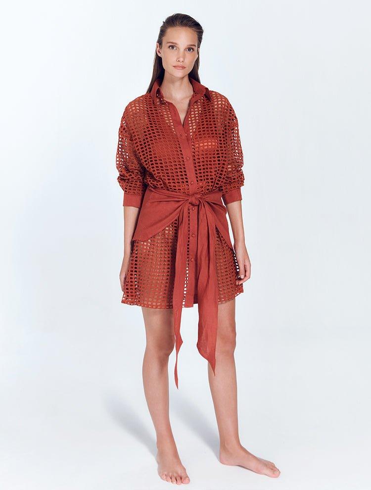 "Jesabel Red Ochre Mini Shirt Dress – Front View, featuring luxury Broderie Anglaise cotton with a button front, pointed collar, and waist tie for a refined vacation look."