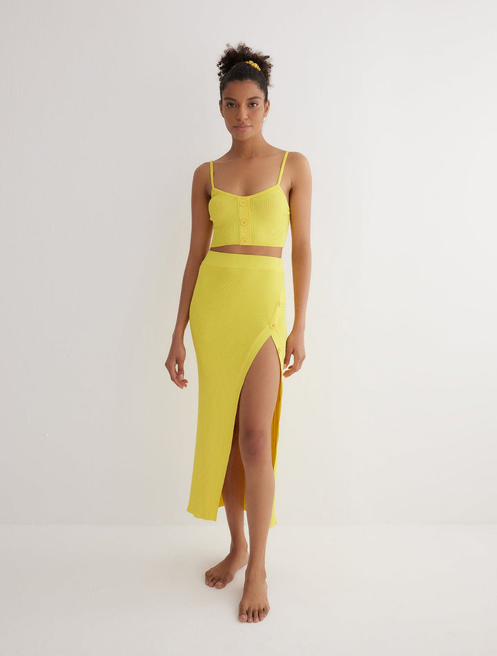 Front View: Model in Jules Yellow Skirt - MOEVA Luxury Swimwear, Knitted Skirt, Button Detail Throughout, Side Assymmetrical Skirt, Elasticated Waistband, Front Slit, MOEVA Luxury Swimwear