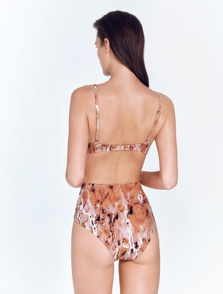 "Model wearing Kai Floral Abstract Swimsuit, featuring adjustable straps and gold clasps."