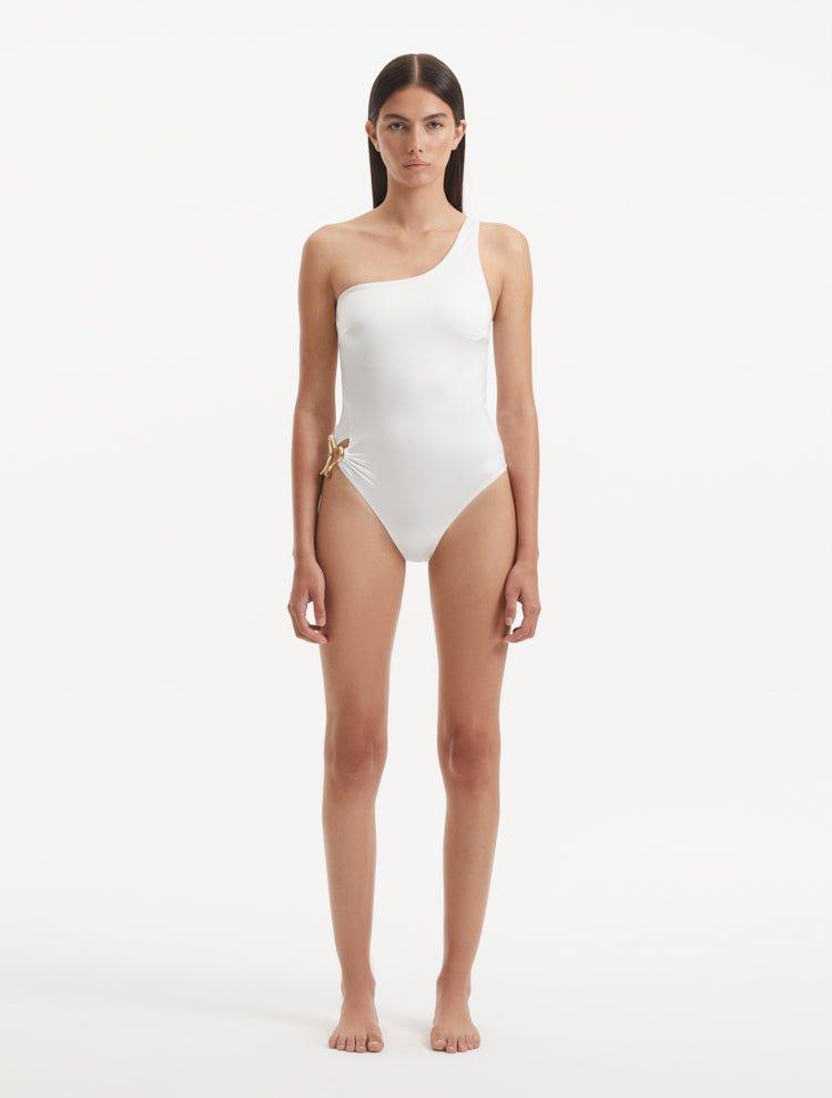 Model showcasing the Kaimana White Swimsuit, highlighting the one-shoulder design and elegant gold sculpted accessory.