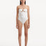 Model showcasing the Kenna White Swimsuit with its elegant strapless neckline and gold sculpted accessory detail.