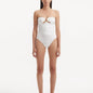 Model showcasing the Kenna White Swimsuit with its elegant strapless neckline and gold sculpted accessory detail.