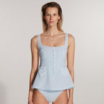 "Model wearing the Kimberley Gingham Baby Blue Swimsuit from the front, featuring a fitted waistline, short circle skirt, and fabric-coated button details, capturing a retro ballerina-inspired design."
