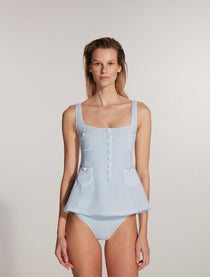 "Model wearing the Kimberley Gingham Baby Blue Swimsuit from the front, featuring a fitted waistline, short circle skirt, and fabric-coated button details, capturing a retro ballerina-inspired design."