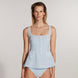 "Model wearing the Kimberley Gingham Baby Blue Swimsuit from the front, featuring a fitted waistline, short circle skirt, and fabric-coated button details, capturing a retro ballerina-inspired design."