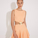 "Front view of the Lanao orange cut-out knitted dress showcasing the high neck, thigh-length hem, and torso-baring cut-outs at the waist with a gold accessory for an elegant look."