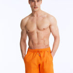 Front View of Model Wearing Louis Orange Shorts- Close Fitting, Lightweight Fabric with Quick Drying, Pockets at the Front, MOEVA Luxury Swimwear 