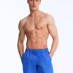 Front View of Model Wearing Louis Sax Blue Shorts- Close Fitting, Lightweight Fabric with Quick Drying, Pockets at the Front, MOEVA Luxury Swimwear 