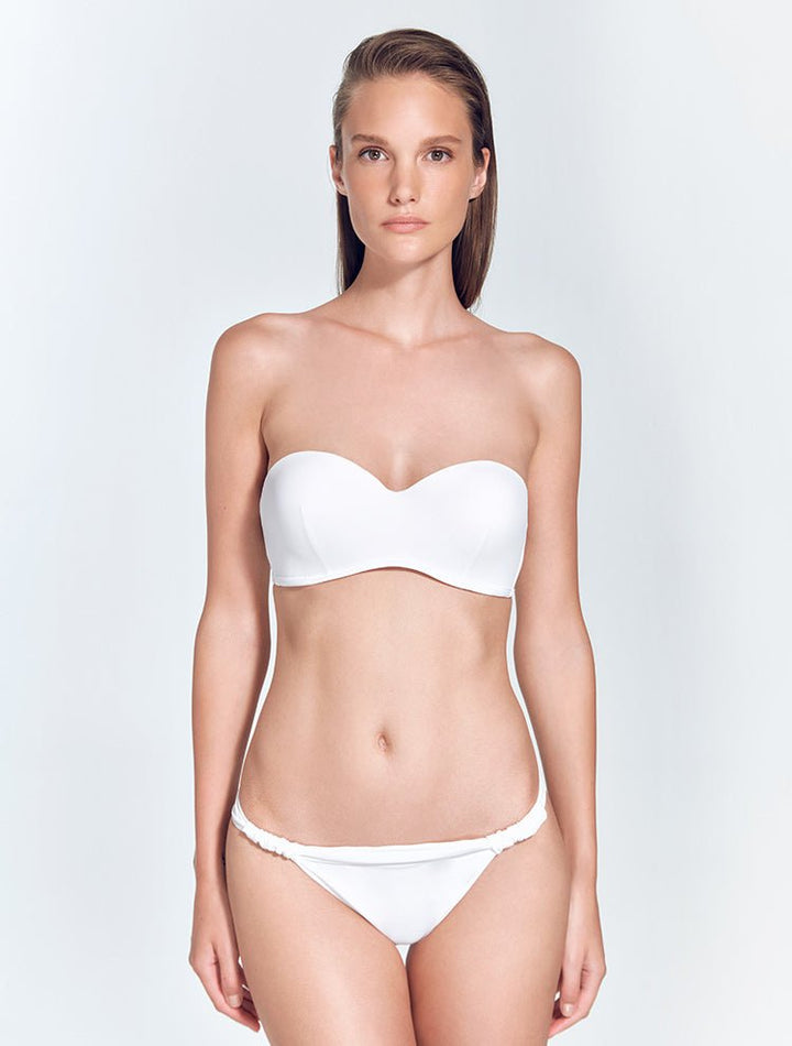 Front View: Model in Lucille White Bikini Bottom - MOEVA Luxury Swimwear, Ruched Details, Brazilian Bottom, Butt Lifting Effect, Low Rise, MOEVA Luxury Swimwear