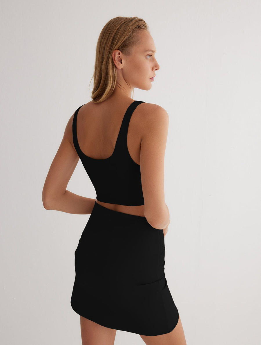 Back View: Model in Lupe Black/Camel Skirt - MOEVA Luxury Swimwear, Mid-Thigh Length, Stretchy Fabric, MOEVA Luxury Swimwear
