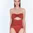 "Model wearing the Madeline Red Ochre Swimsuit from the front, showcasing the bandeau design and natural stone accents."