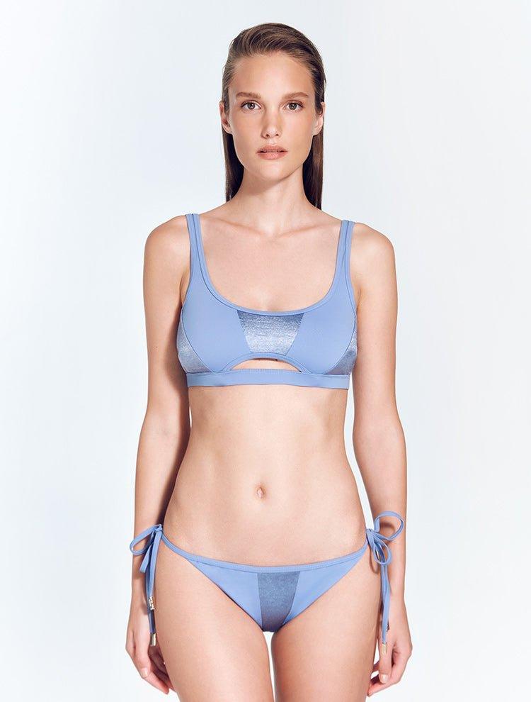 "Model wearing the Maelys bikini bottom with a low-rise waist and contrasting satin and matte fabric panels. The front view highlights the stylish design and small coverage."