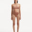  Model showcasing the Marilla Brown Swimsuit, highlighting the high-waist style and strapless design with cut-out detail.