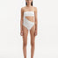 Model showcasing the Marilla White Swimsuit, highlighting the high-waist style and strapless design with cut-out detail.