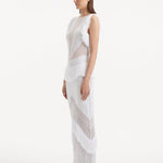 "Side view of the Maris White Dress, emphasizing the close-fitting silhouette, fringe details at the hem, and the gentle contour of the dress as it moves."