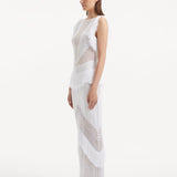"Side view of the Maris White Dress, emphasizing the close-fitting silhouette, fringe details at the hem, and the gentle contour of the dress as it moves."