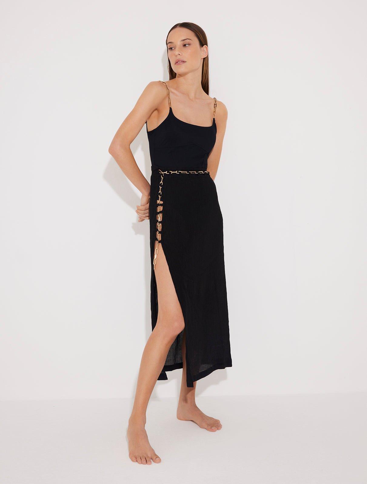 Front View: Model in Maritza Black Skirt - MOEVA Luxury Swimwear, Side Slit, High Rise, Elastic Waistband, Geometrical Chain Belt, MOEVA Luxury Swimwear