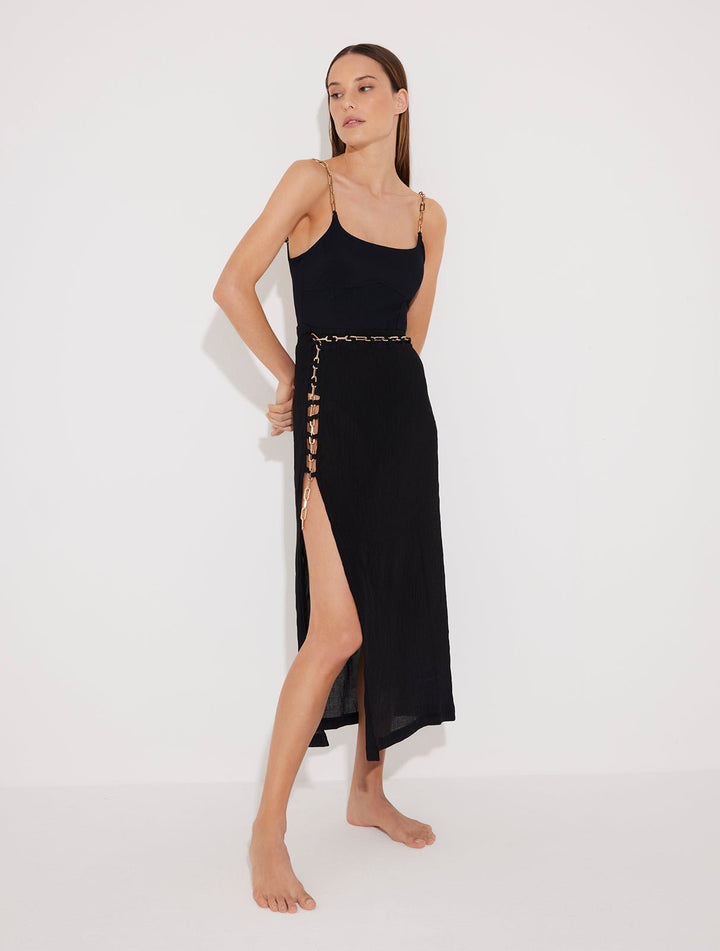 Front View: Model in Maritza Black Skirt - MOEVA Luxury Swimwear, Side Slit, High Rise, Elastic Waistband, Geometrical Chain Belt, MOEVA Luxury Swimwear