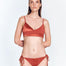 "Front view of model in Melody Red Ochre Bikini Top – Wrap-effect front with adjustable straps and gold clasps."