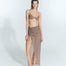 "Front view of a model wearing the Millie Nude Skirt with ruched detailing, a front slit, and transparent fabric.