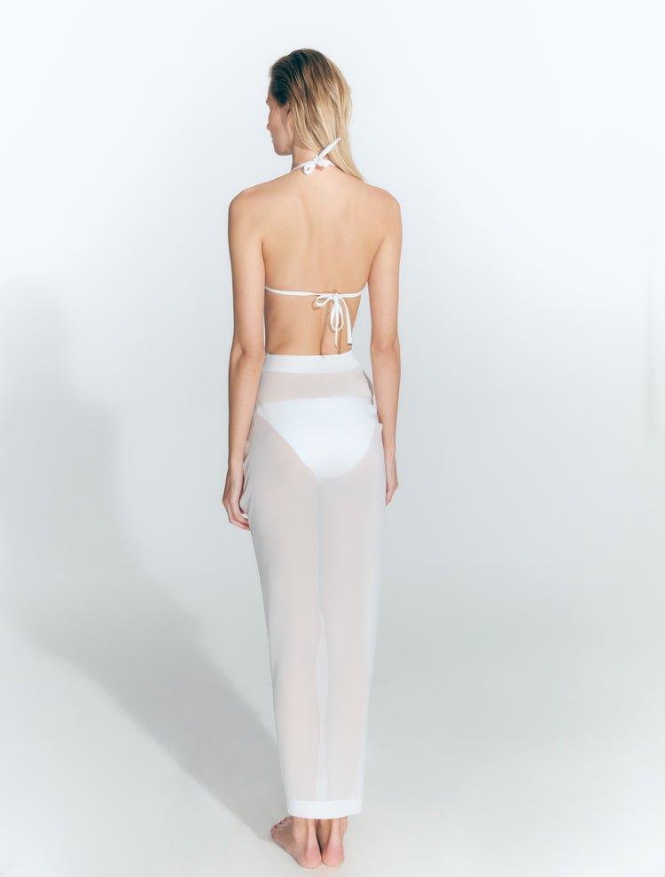 "Back view of a model wearing the Millie White Skirt, showcasing the ruched detailing along the waist, the adjustable fit, and the transparent fabric with a subtle front slit."