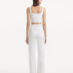 "Model wearing the Moira White Pants from the back, emphasizing the smooth, high-waisted style and wide-leg silhouette."