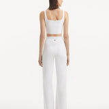 "Model wearing the Moira White Pants from the back, emphasizing the smooth, high-waisted style and wide-leg silhouette."