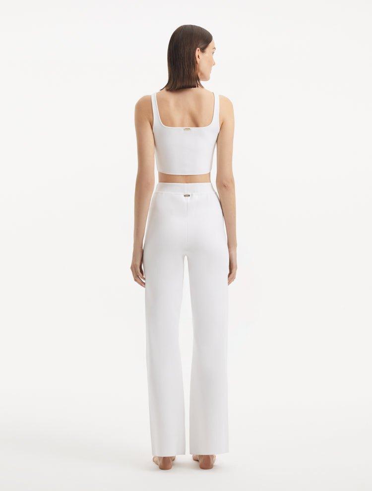 "Model wearing the Moira White Pants from the back, emphasizing the smooth, high-waisted style and wide-leg silhouette."